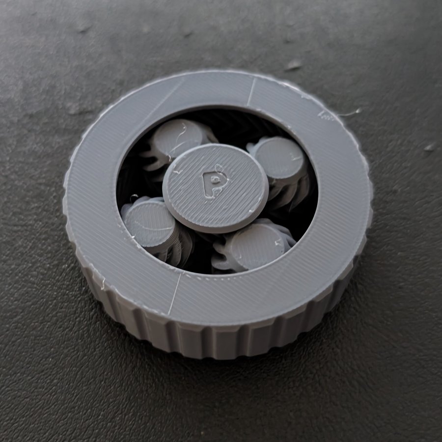 Photo of attempt 10 printed in one colour grey: a knurled ring around four herringbone planet gears and a sun cap embossed with a P