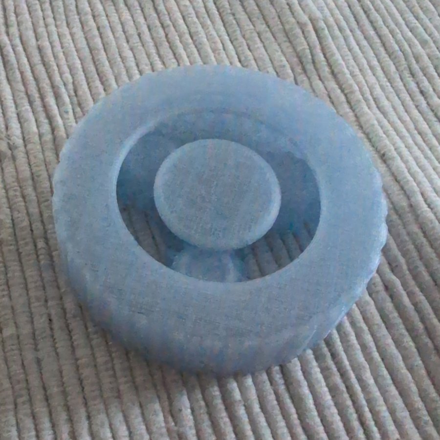 Photo of attempt 9 printed in one colour pale blue PLA, assembled, on a ribbed fabric surface